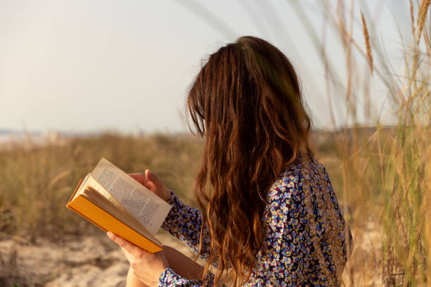 istock Woman reading book at the beach 1857329509