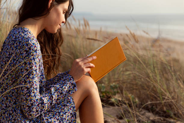 istock Woman reading book at the beach 1857329566