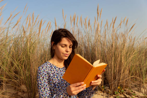 istock Woman reading book at the beach 1857330668