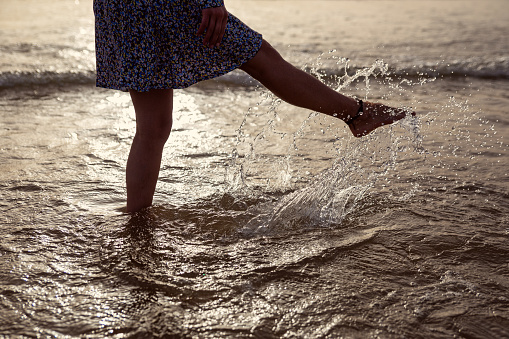Woman splashing water with her legs at the sea