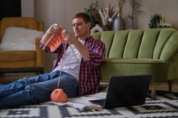 istock enthusiastic ginger guy wearing a red checkered shirt is mastering the art of knitting while watching a step-by-step guide on his laptop. From Beginner to Pro: A Guide to Knitting for Men 1857351455