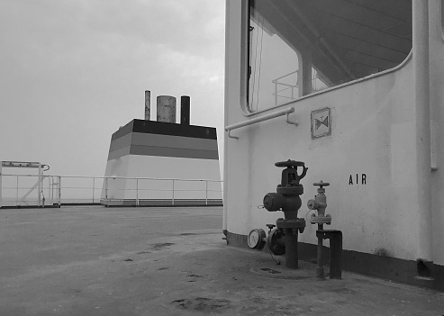 View of the funnel and stern of a merchant ship at sea, with a fire hydrant in the foreground