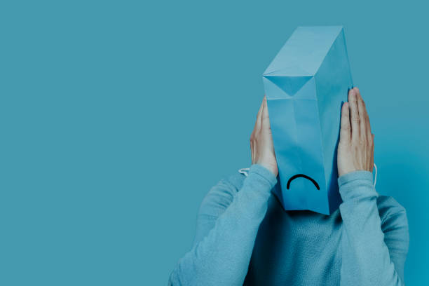 hombre con una bolsa azul con una cara triste en la cabeza - adicto a las compras fotografías e imágenes de stock