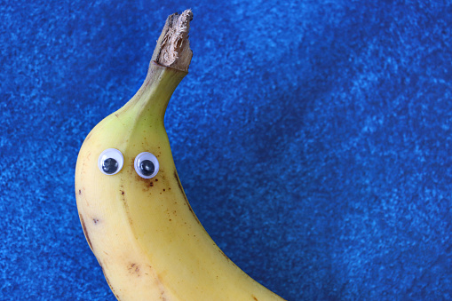 Stock photo showing a close-up view of ripe banana made into cartoon character with googly eyes for a touch of humour. Fun way to encourage healthy eating in children.