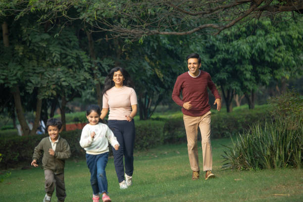 istock Parents running behind children in park 1857429981