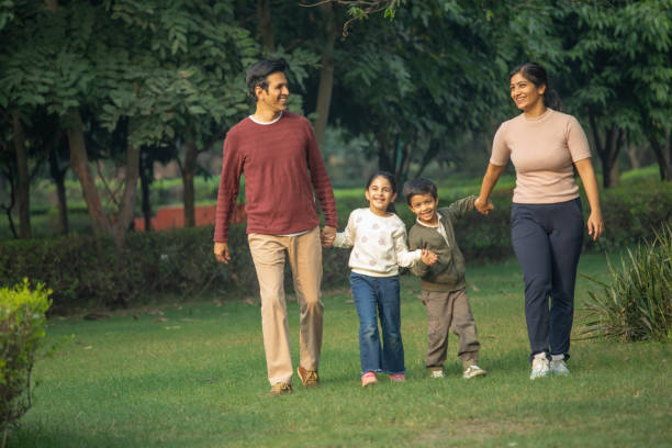 istock Happy parents and children walking in park 1857444721