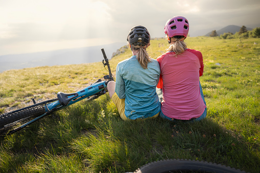 Two mid adult caucasian women riding electric mountain bikes together full length front view