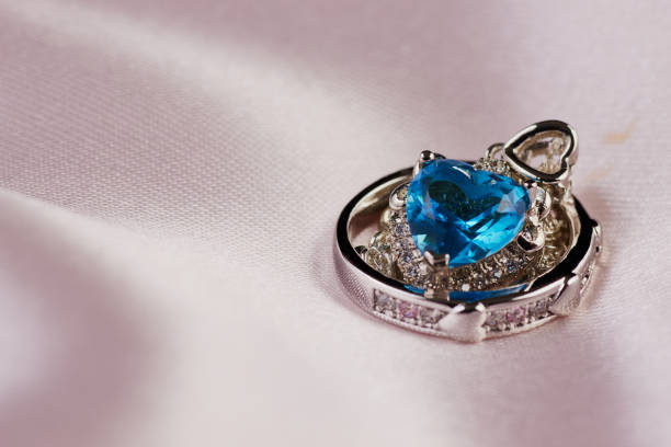 istock Heart Shape Blue Diamond Necklace and Wedding Ring on Fabric 1857446844