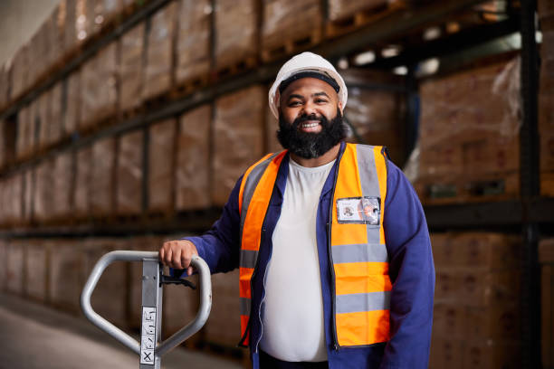 istock Smiling male engineer standing with a pallet jack in a shipping warehouse 1857450054