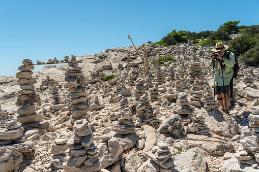 Senior men photographing stacks of stones against clear blue sky in Telascica, national park in Dugi otok island, Croatia