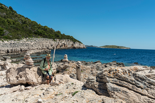Senior men walking along many stacks of stones against clear blue sky in Telascica, national park in Dugi otok island, Croatia