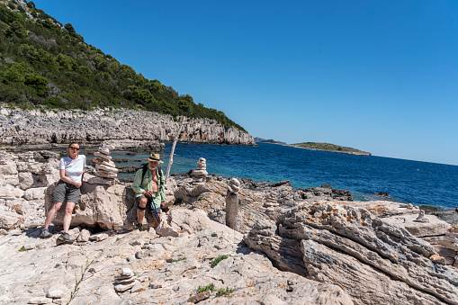 Senior men and women taking photo at many stacks of stones against clear blue sky in Telascica, national park in Dugi otok island, Croatia.