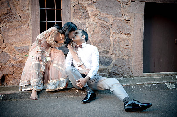 Young indian couple sitting on sidewalk kissing stock photo