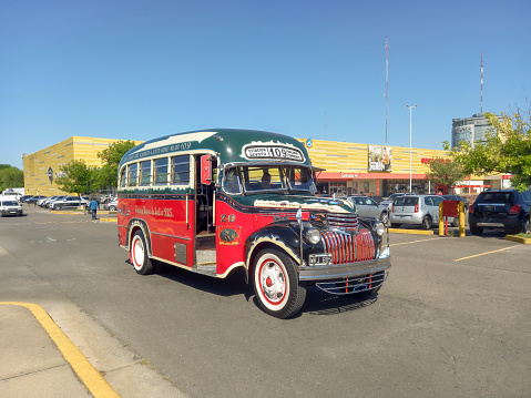 Buenos Aires, Argentina - Dec 10, 2023: old red 1946 Chevrolet AK series bus for public passenger transport in Buenos Aires at a classic car show in a parking lot. Traditional fileteado ornaments. Copy space