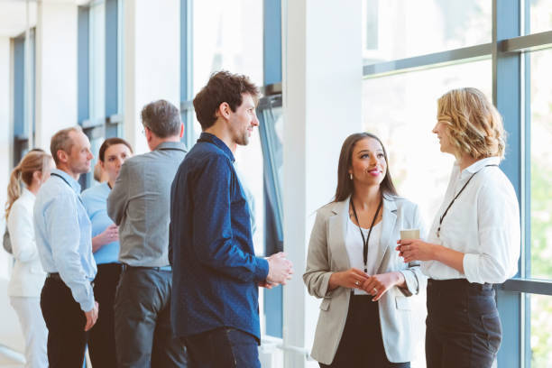 Business people in convention center during coffee break Multiracial group of entrepreneurs discussing during coffee break at business seminar. Group of people standing and talking in the corridor of a business center. Networking concept. social interaction stock pictures, royalty-free photos & images