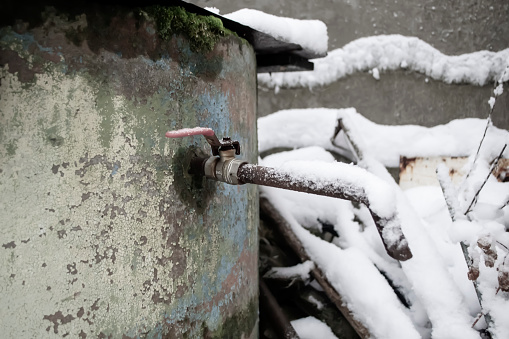 A tap from a well in winter. The crane outside is covered with snow. Plumbing in the winter.