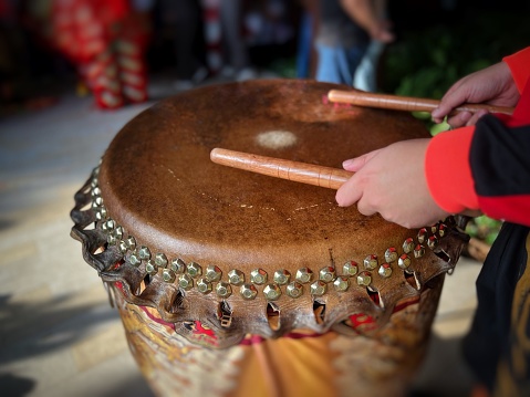 Close-up of adult hand hitting drum with drum sticks for lion dance performance