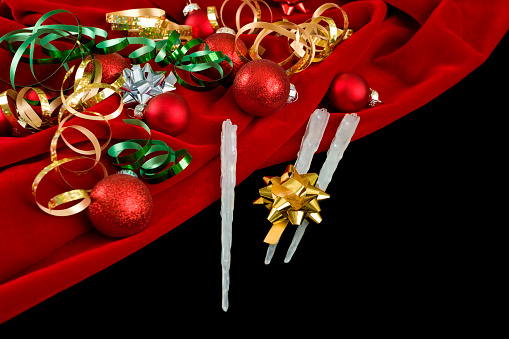 Christmas theme with Christmas balls and gift ribbon and fake icicles on red velvet background with copy space.