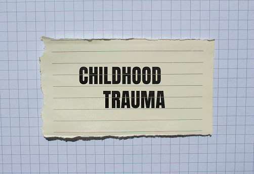 Childhood trauma lettering on ripped paper. Conceptual mental health photo.
