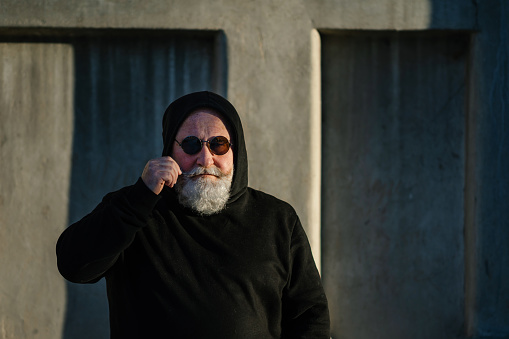 Portrait of a hipster in black hoodie and round sunglasses