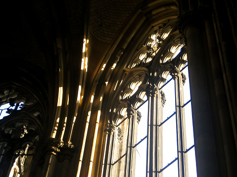 Sunlight shinning in through a cathedral window frame lacking the stain glass.