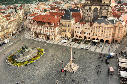 People walk along the medieval cobblestone streets and old historic buildings of Old Town Square by the Jan Hus monument sculpture statue in Prague Czech Republic