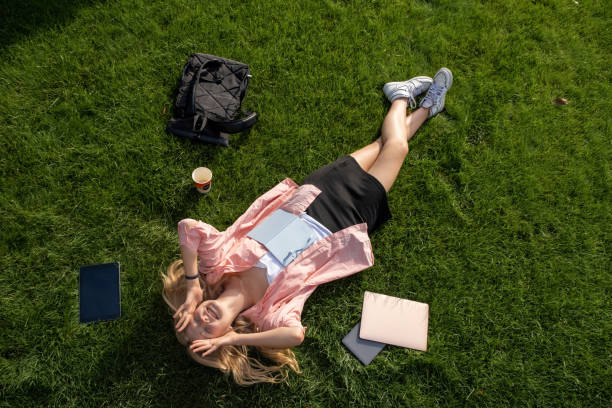 istock Young blonde student rests on green grass after lessons 1857628728