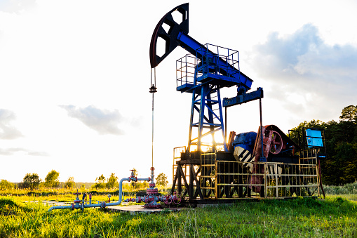 An active oil rig operating at sunrise or sunset. Resource extraction, oil crisis