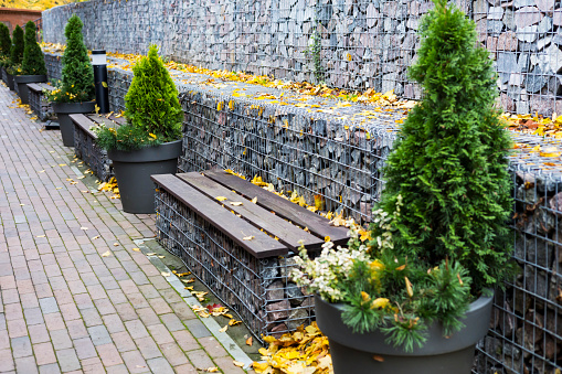 gabion retaining walls. wooden benches built into a dry wall in the park.