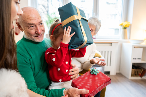 Excited multi-generational family exchanging Christmas presents, during Christmas celebration