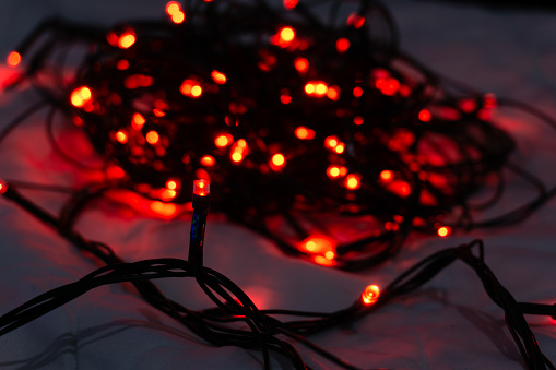red christmas string lights on bedding in dark room close up