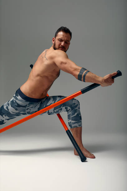 istock A ninja man holds on to a fighting stick and attacks close-up on gray studio background 1857725244