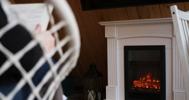 istock Man reading book by fireplace, embodying tranquility in every frame. Cozy, peaceful setting ideal for themes of rest, relaxation. Video exudes calmness, perfect for serene, peaceful content. 1857733512