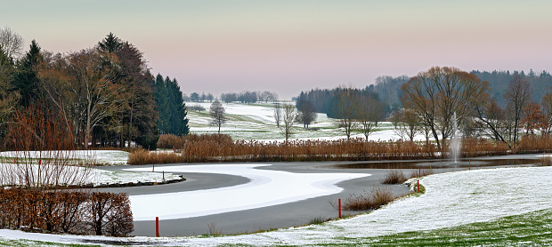 golf course at winter with pond, snow and water fountain in Bath Tatzmannsdorf in the region Burgenland, Austria