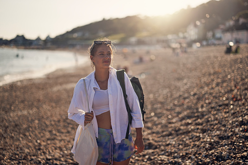 Teenage girl enjoying vacations in Lyme Regis, Dorset, United Kingdom. The girl is walking on pebble beach.\nShot with Canon R5