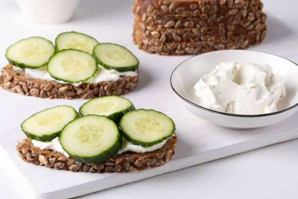 istock Rye bread with cream cheese and cucumbers on a white table. Whole grain rye bread with seeds 1857750093