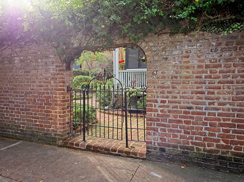 Charleston, South Carolina - USA, November 30, 2023. Brick wall and iron gate entrance to home garden in French section of Charleston South Carolina. Southern charm architecture along Meeting street in Charleston.