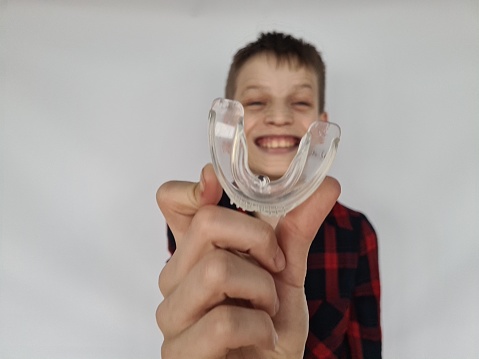 Smiling boy with Invisalign braces and mouth guard. Concept of orthodontic oral care for teenager