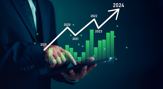 Businessman calculates financial data for long term investments. Column chart with company progress and growth by year, 2024, Business growth planning. Investments, financial business analytics.