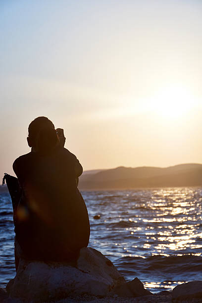 istock woman making phone call with sunset at beach 185788263