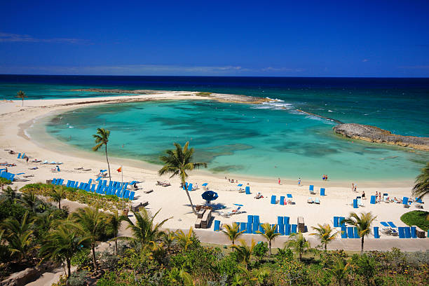 Vibrant tropical beach featuring crystal-clear blue waters and bright white sandy shores beneath a sunny sky scattered with fluffy clouds, suitable for vacations, travel inspiration, and relaxation scenes.
