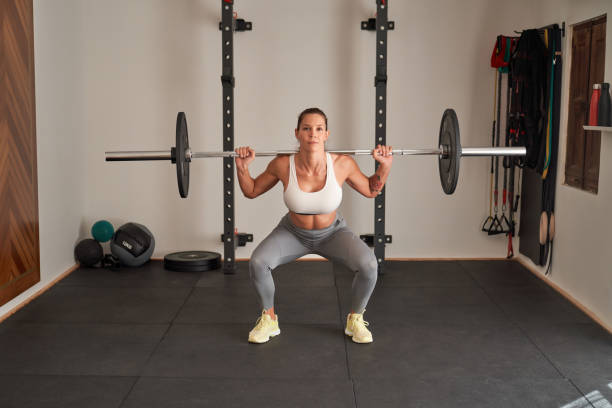istock Fit woman doing barbell squats with heavy weights 1857920804