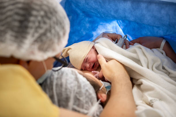 Mother and newborn daughter by cesarean section Mother and newborn daughter by cesarean section - Doctors performing a cesarean section in the operating room - Buenos Aires - Argentina new life stock pictures, royalty-free photos & images
