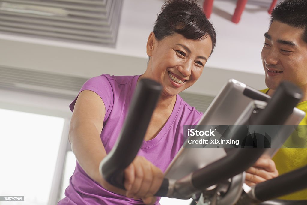 Женщина, физические упражнения на велотренажер с ее тренером - Стоковые фото Велотренажёр роялти-фри