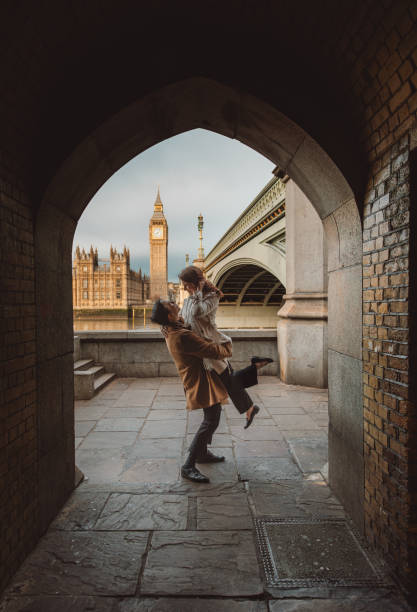 happy and young tourist couple enjoying a romantic getaway in iconic streets of london city, england, united kingdom - romantic getaway stock-fotos und bilder