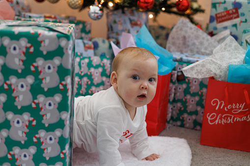Surprised baby in awe amongst Christmas presents and decorations