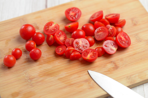 Freshly cut cherry tomatoes on a bamboo board, vibrant red hues.