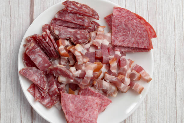 salami in scheiben geschnitten und gehackter speck fertig zum kochen. - delicatessen meat cold cuts chopped stock-fotos und bilder