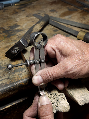 A jeweller measuring a ring hi is working on with a tool called callipers.
