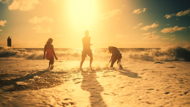 silhueta de três amigos se divertindo na praia - silhouette three people beach horizon - fotografias e filmes do acervo